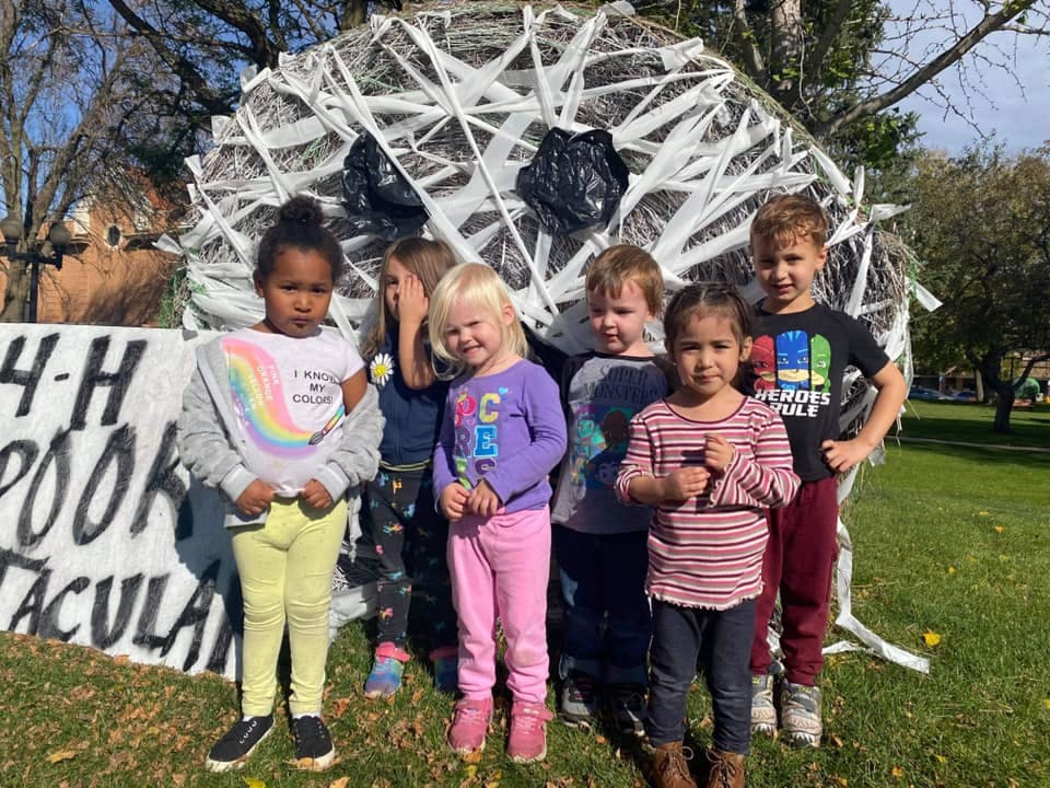 Six children standing in front of a white web-like structure