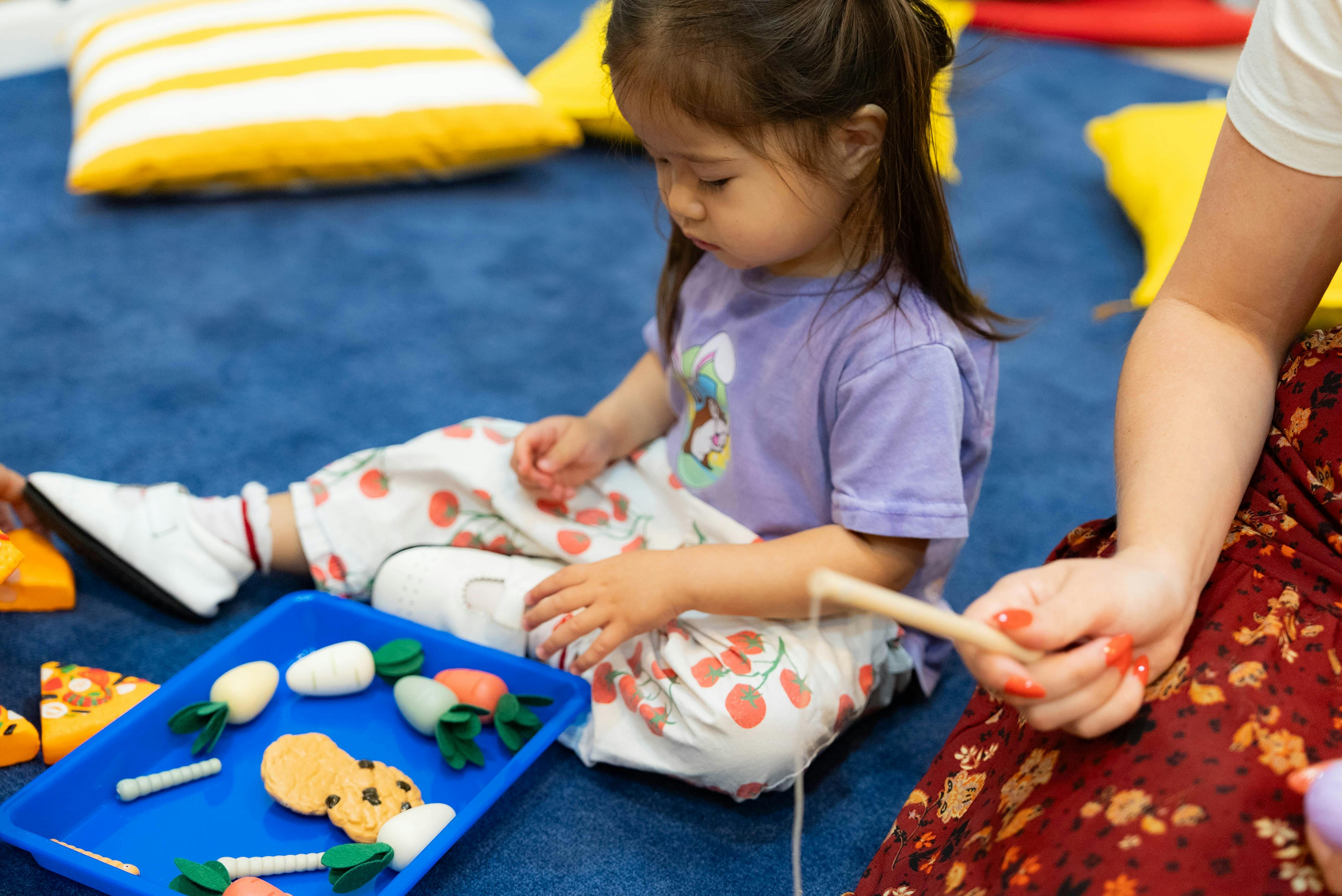 Child playing with toy food on a blue tray