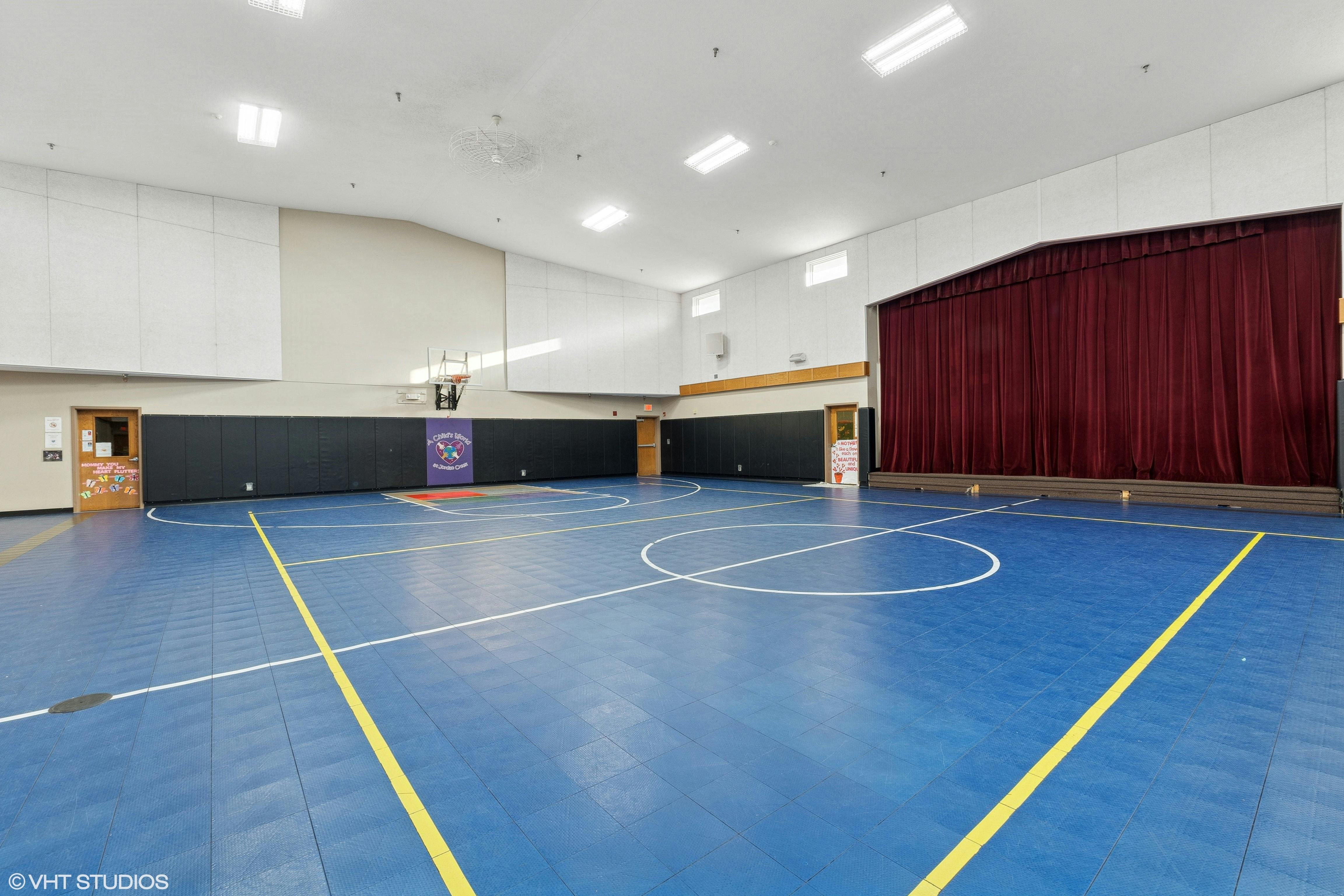 Indoor gymnasium with blue floor and white and yellow court lines