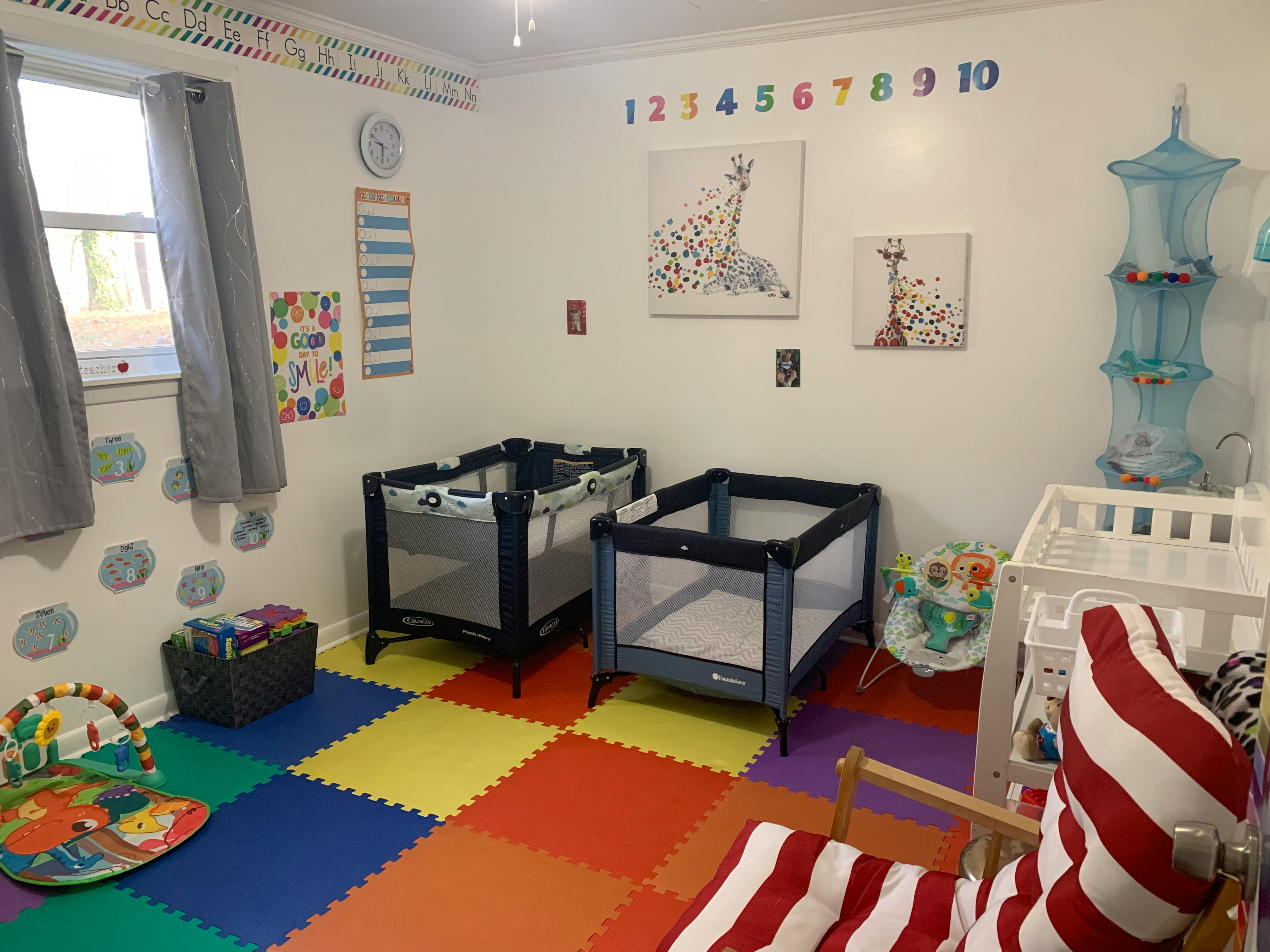 Baby room with two cribs, a changing table, and a colorful playmat on puzzle-piece flooring