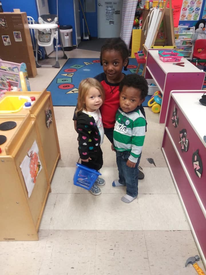 Three children standing together in a classroom