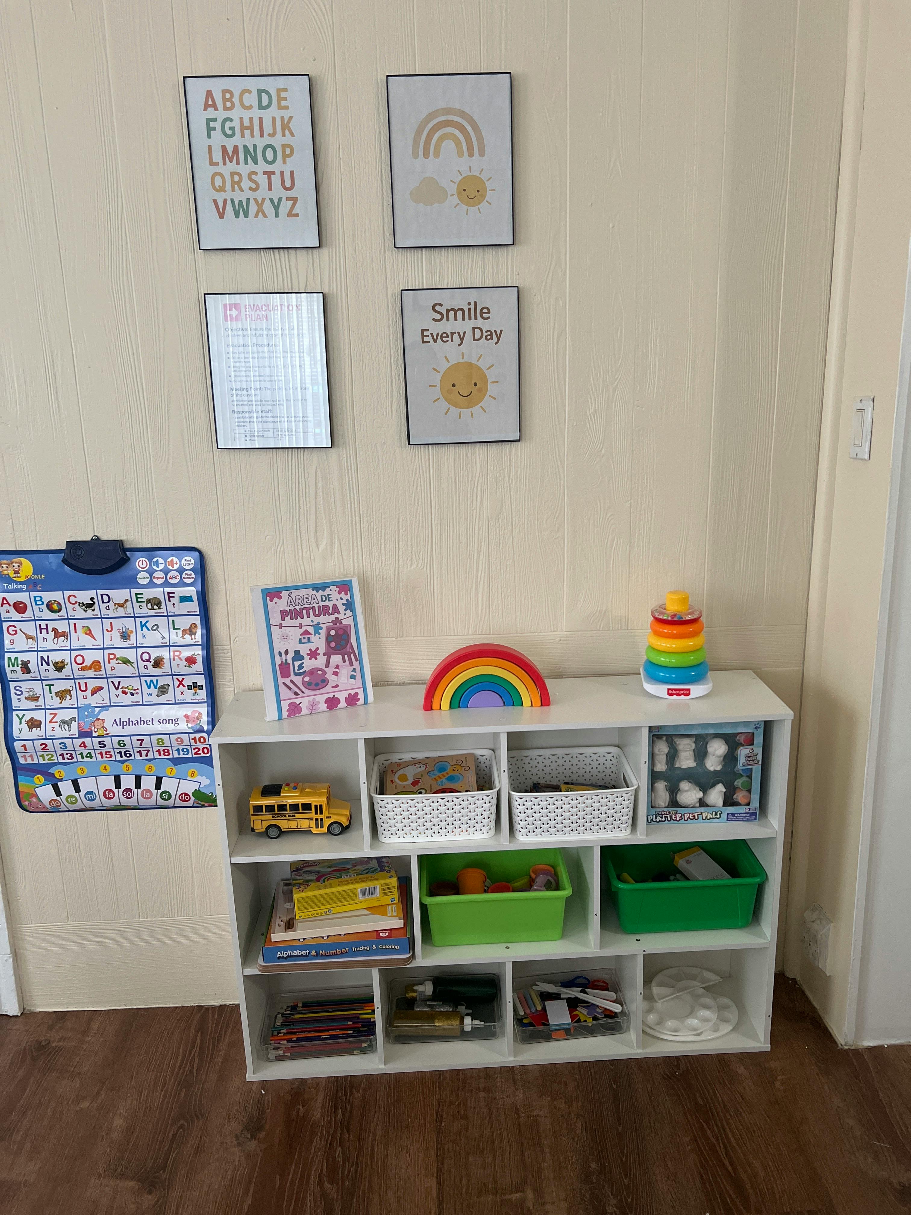 Wall with alphabet and sun pictures, a toy shelf with a rainbow and stacking toy