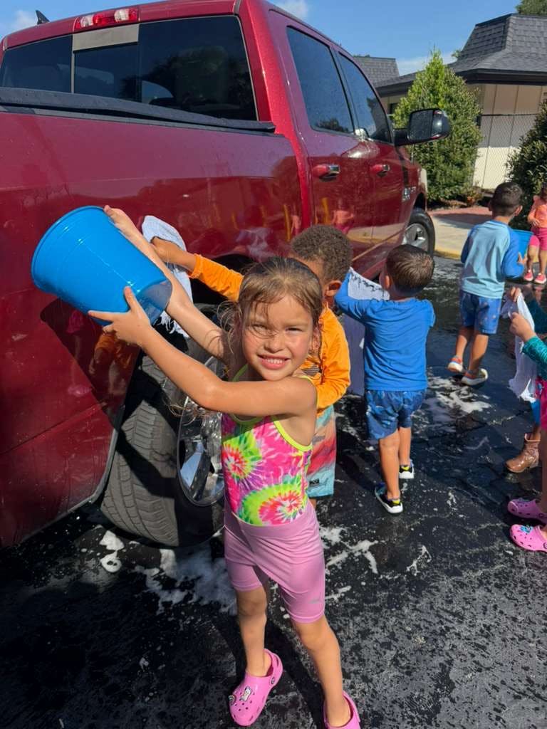 Group of children washing a pickup truck outdoors