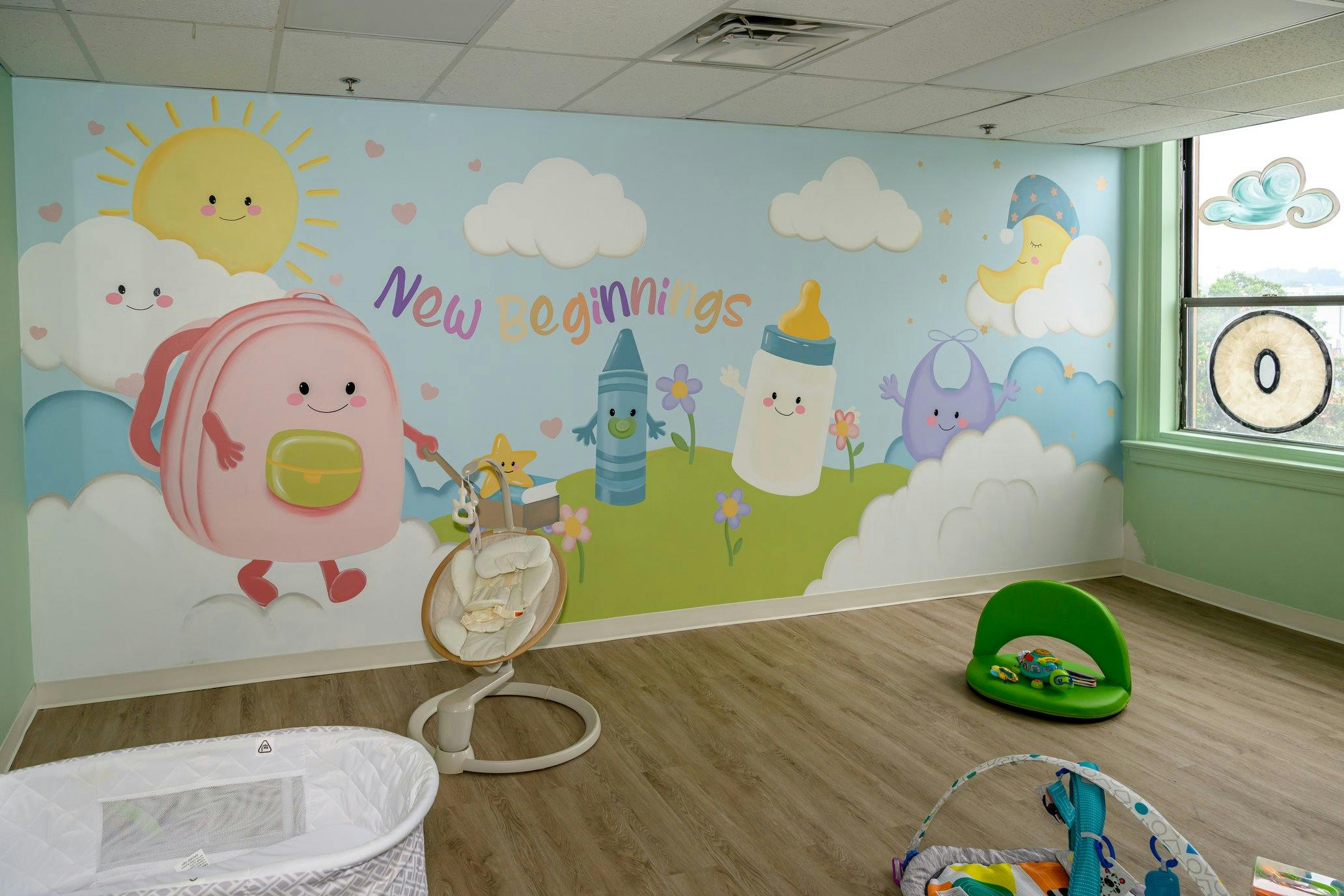 Nursery room with a cartoon New Beginnings wall mural and baby equipment