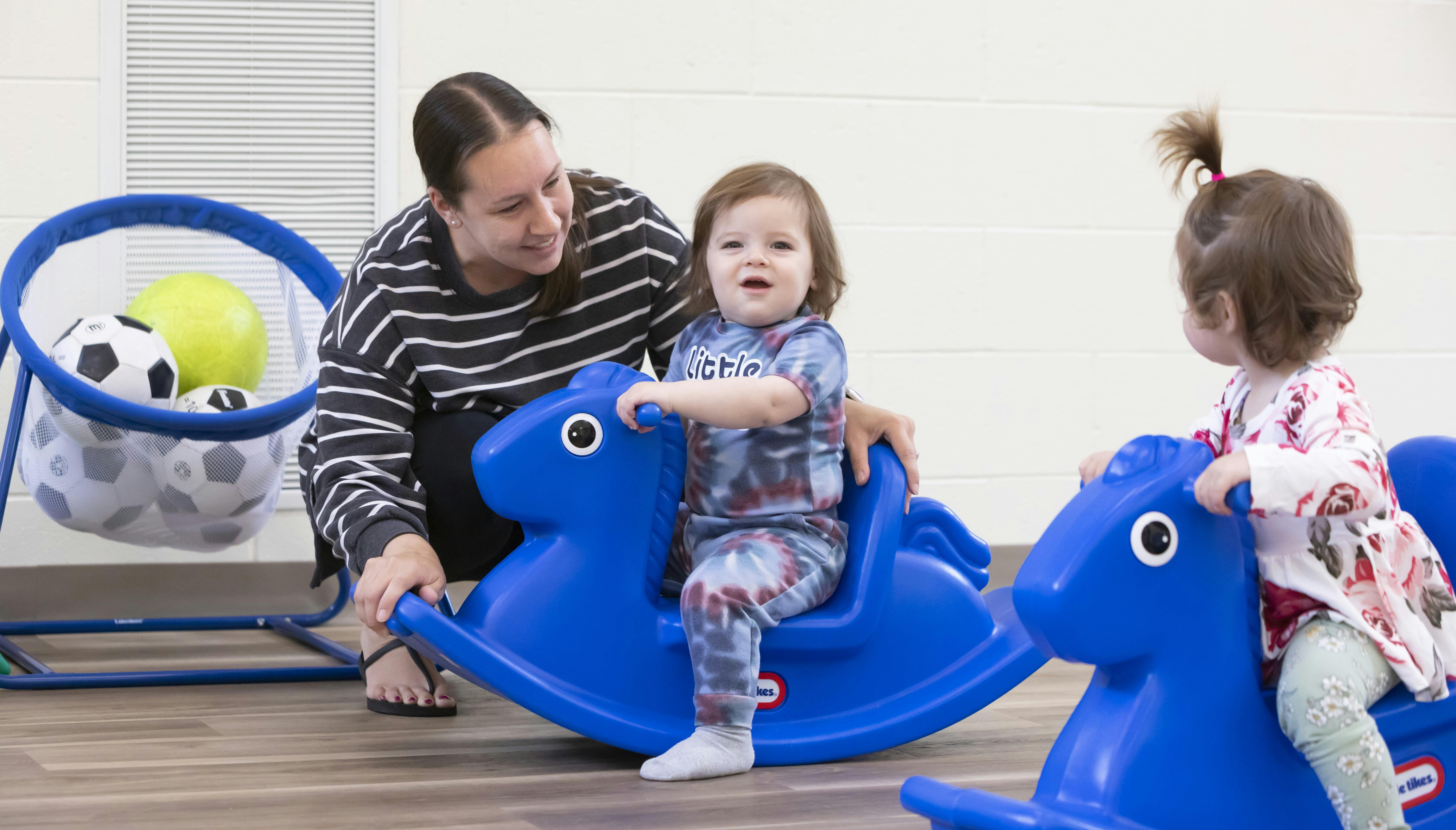 Person with two children on blue rocking horses