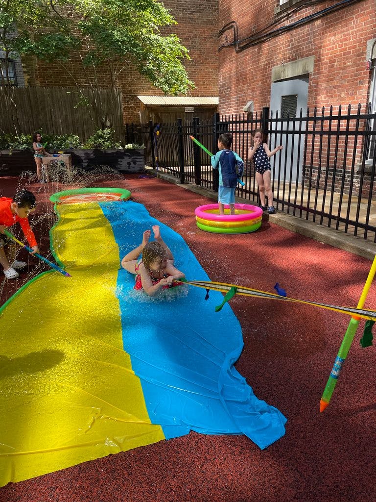 Children playing with water slide and squirt guns outdoors