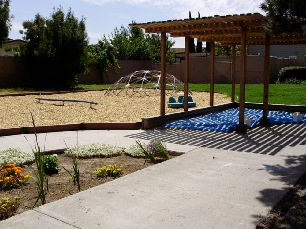 Playground with a climbing dome, seesaw, and a shaded area with blue mats