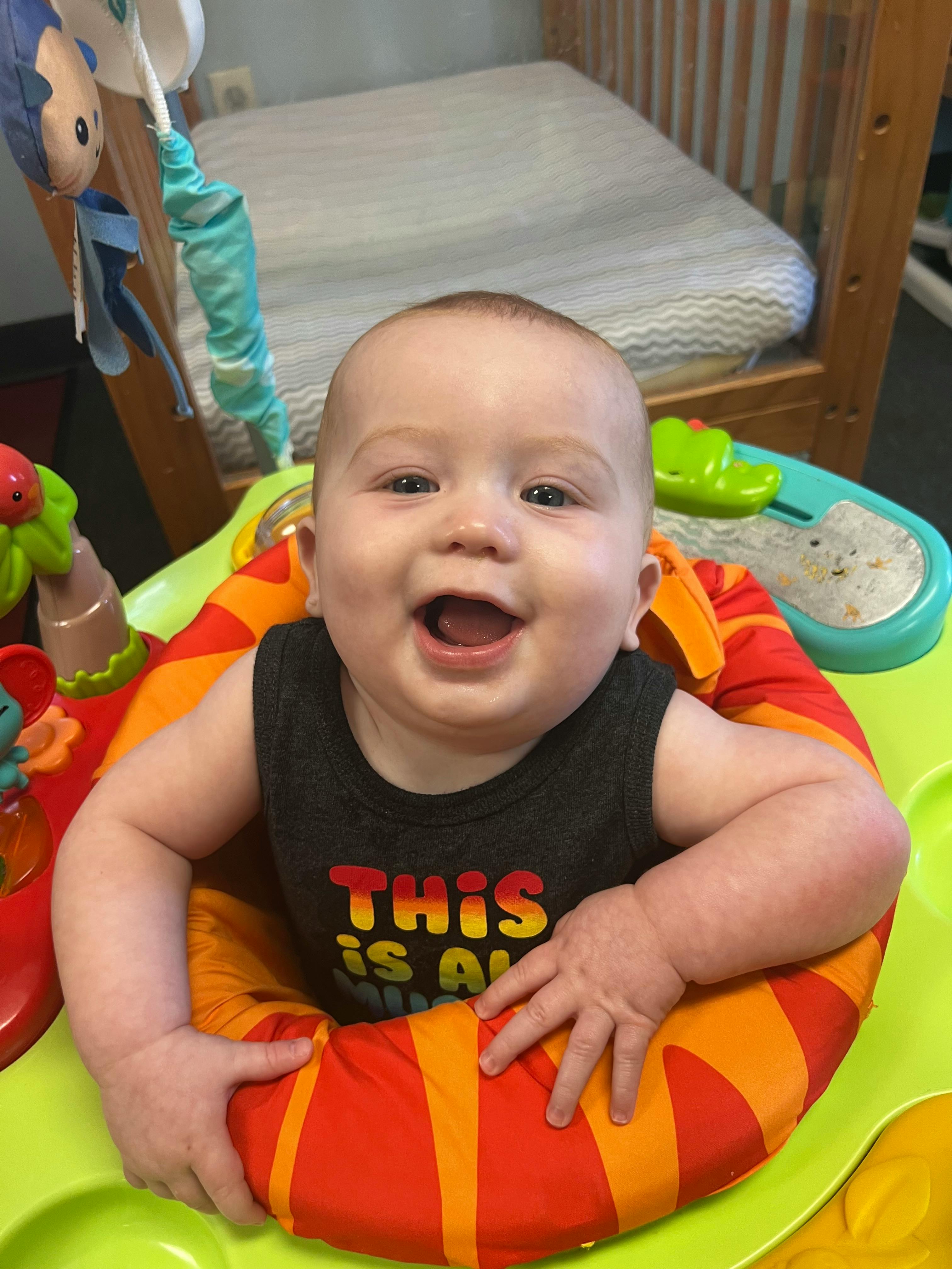Child in a baby bouncer with a wide open mouth