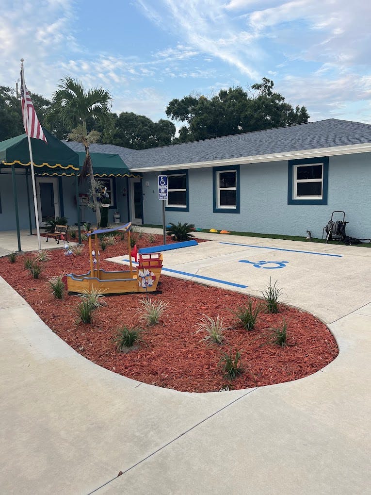 Building exterior with a green awning, flag, and a small boat-shaped planter