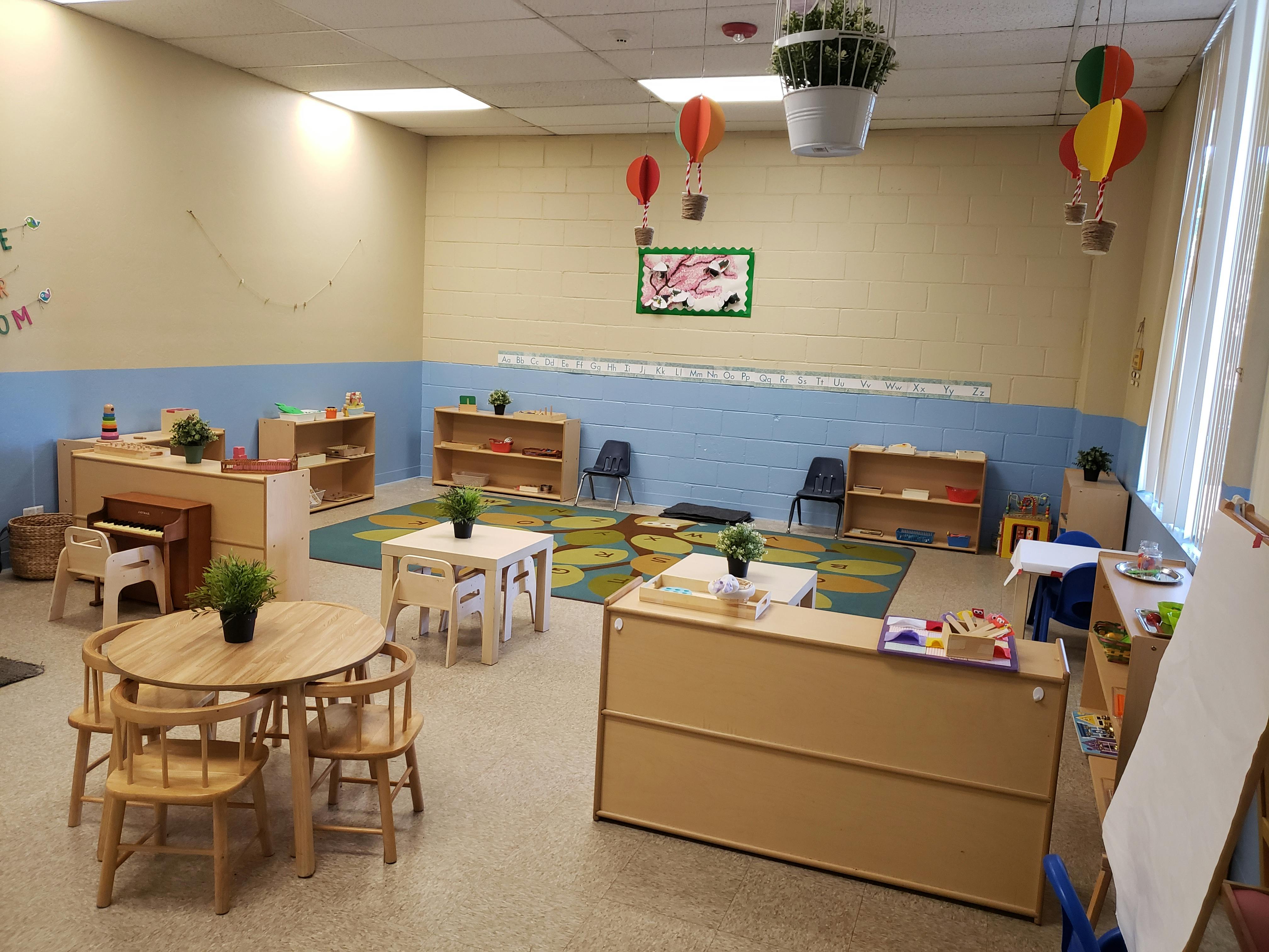 Classroom with small tables and chairs, shelves, and hot air balloon decorations