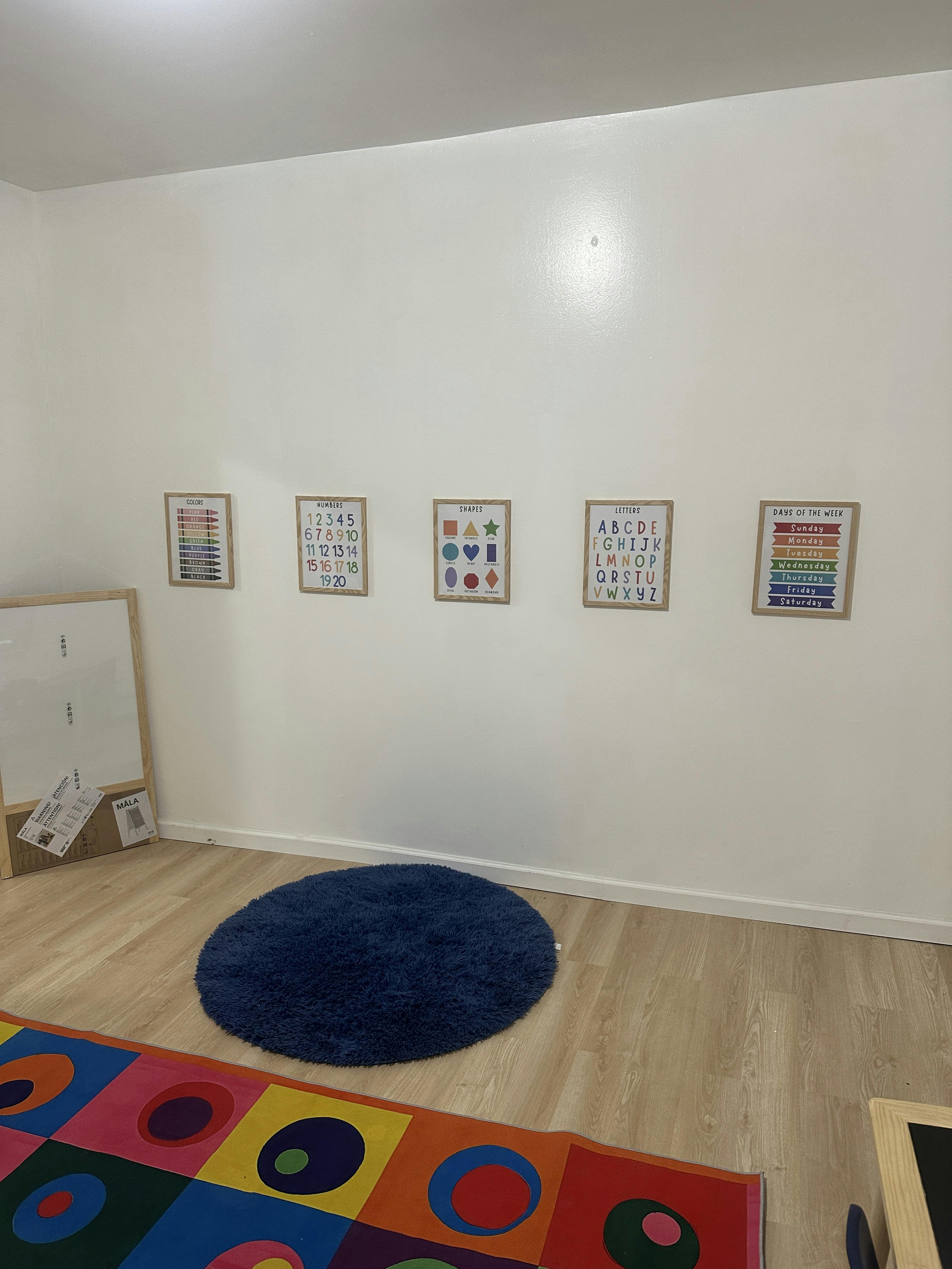 Classroom with educational posters on the wall and colorful rugs on the floor