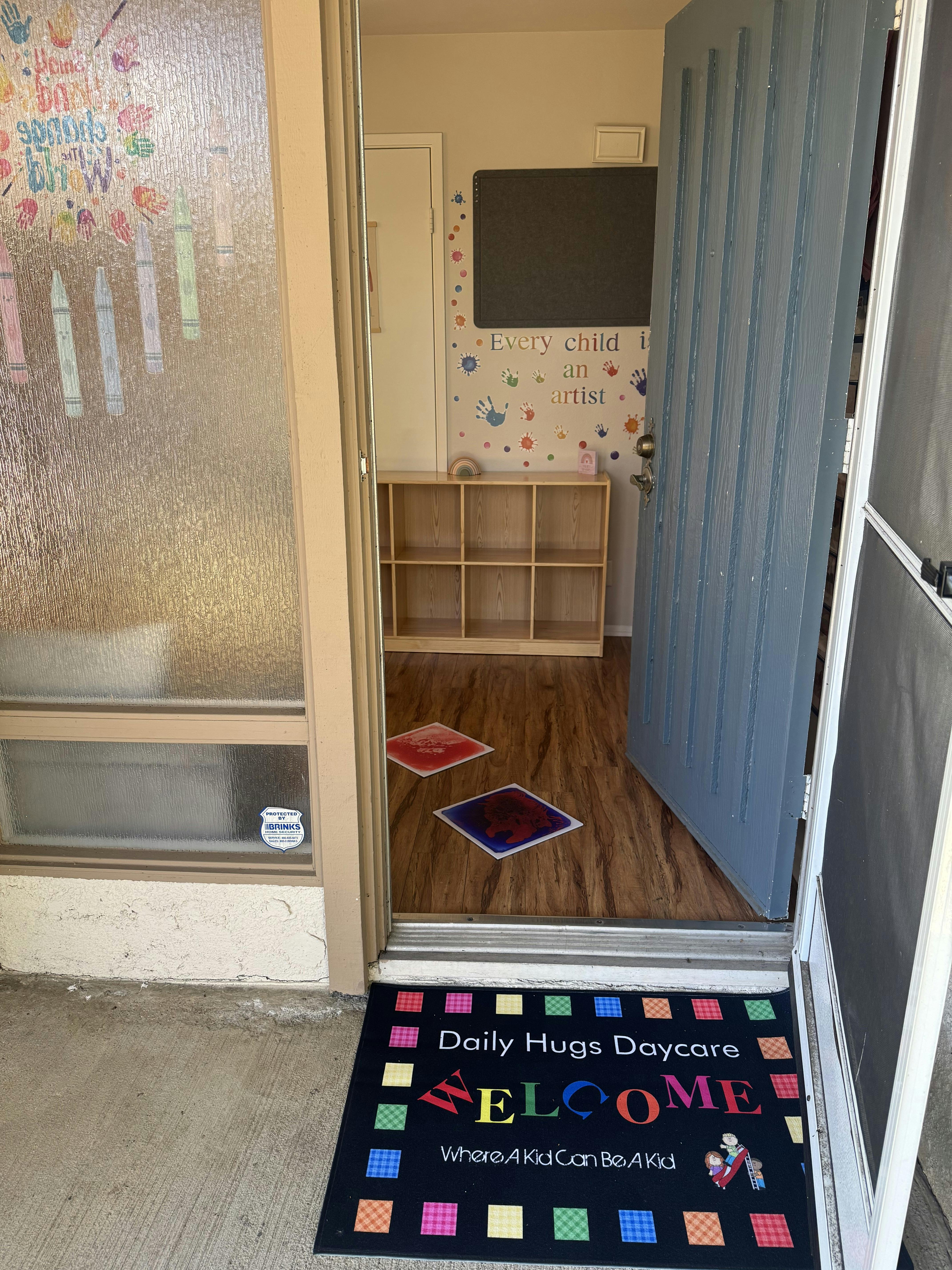 Welcome mat outside a door with "Daily Hugs Daycare" and "WELCOME"