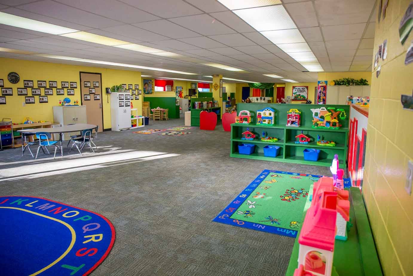 Empty classroom with colorful rugs and shelves of shelves of toys