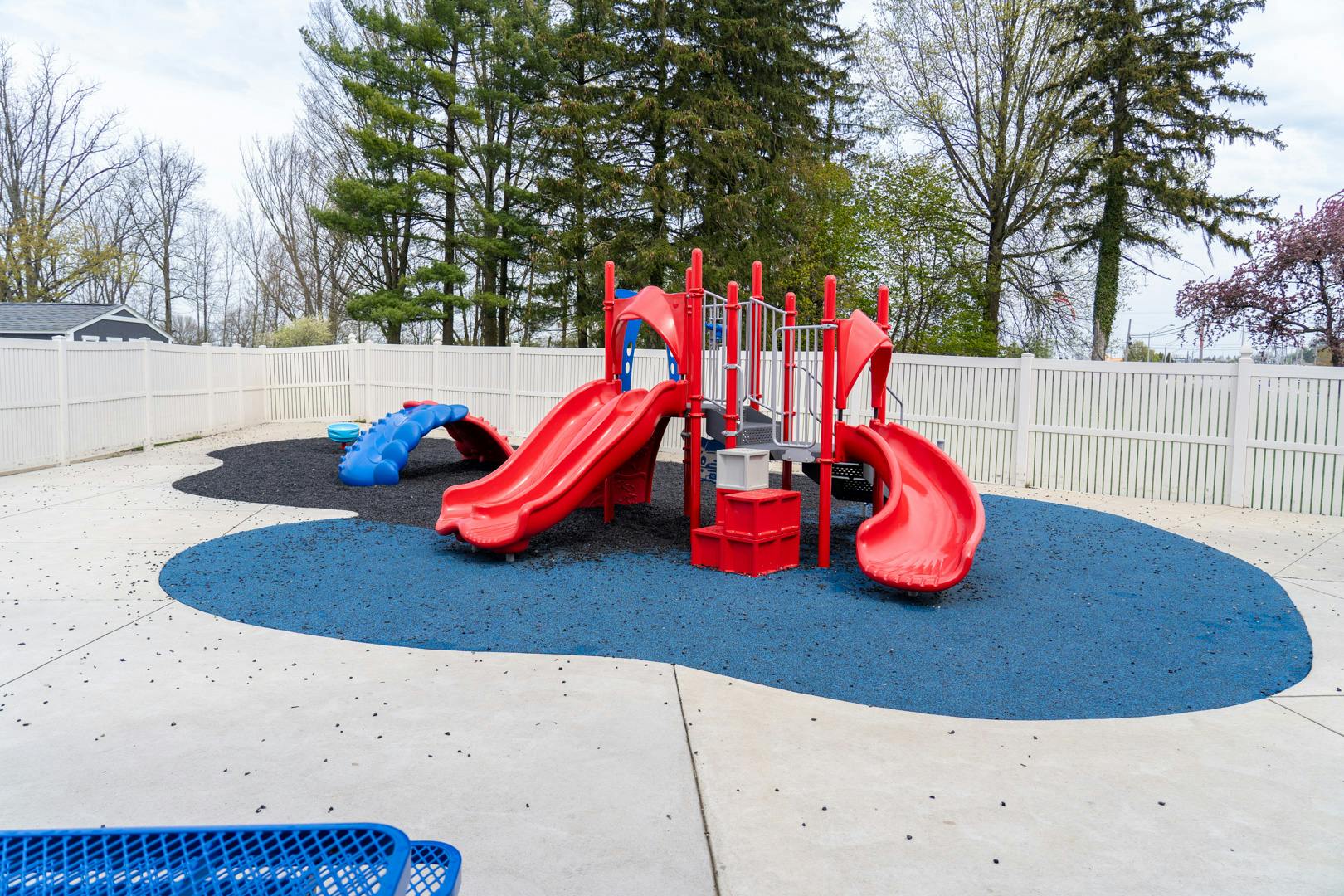 Red and blue playground equipment on a blue and black soft surface