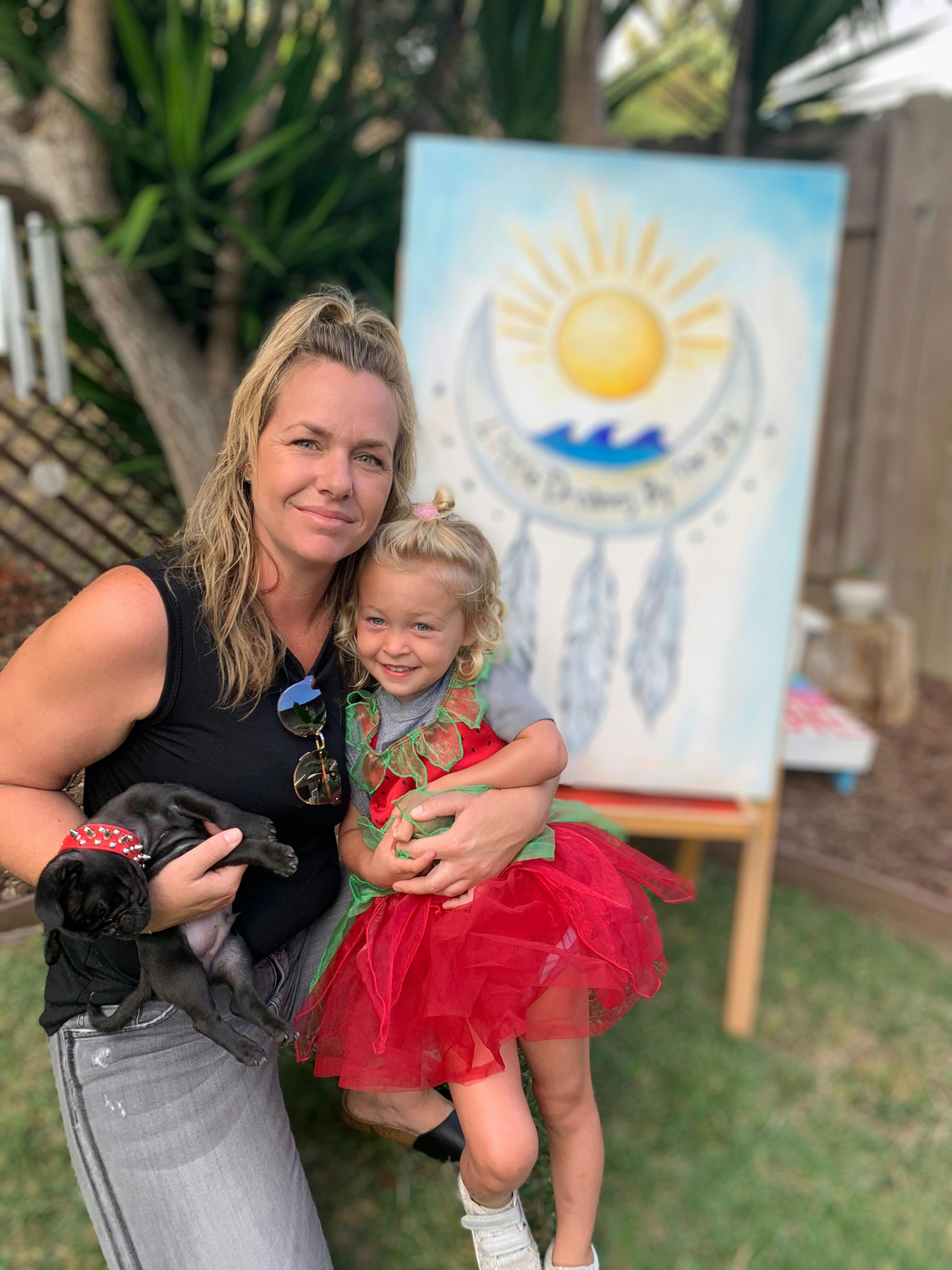 Person holding a small dog and a child in a red dress