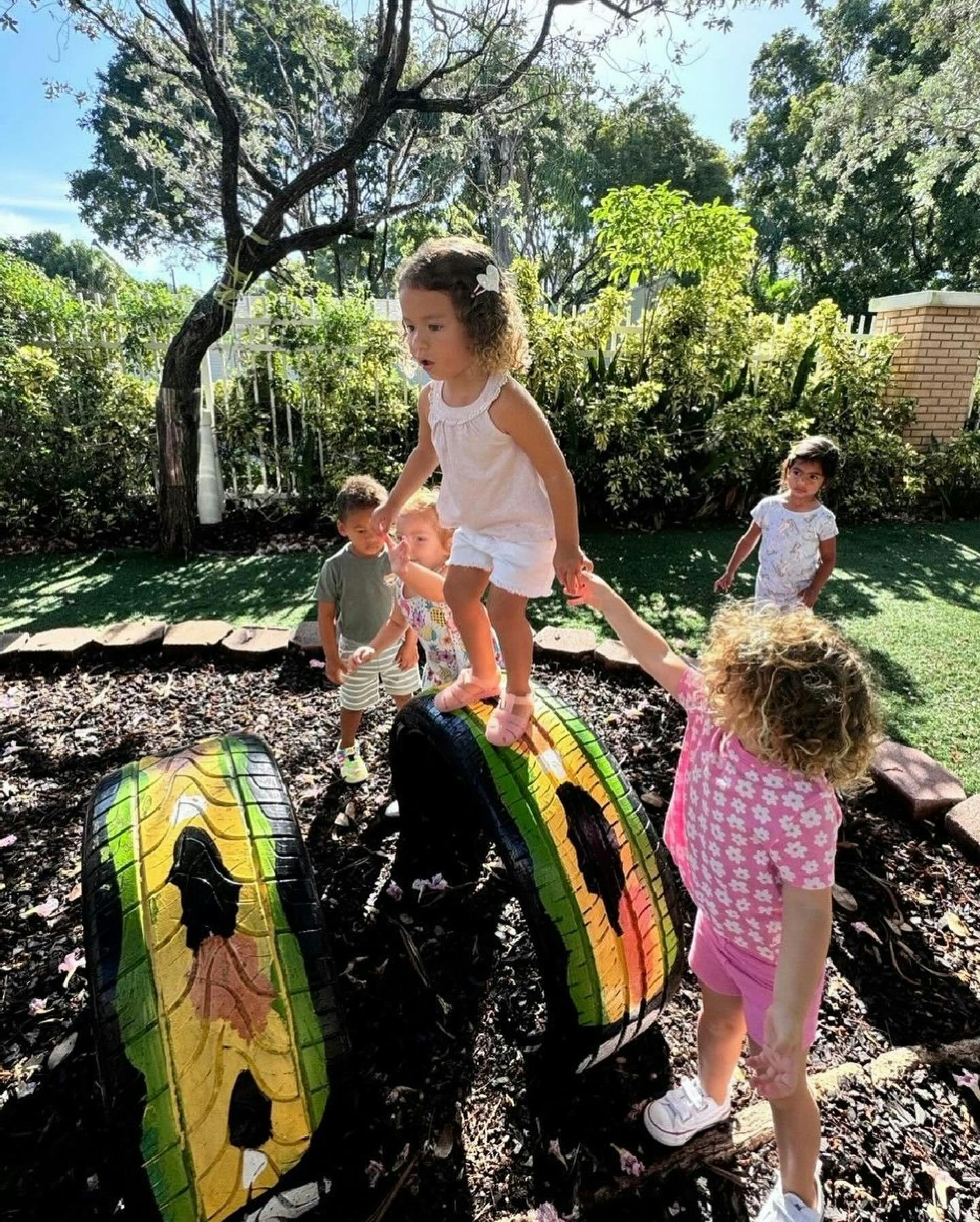 Children playing on painted tires in a garden