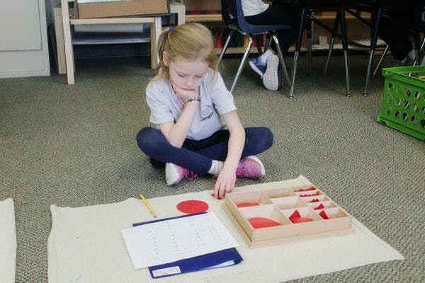 Child sitting on floor working with learning materials in a classroom