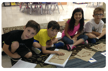 Four children sitting on a rug with craft materials
