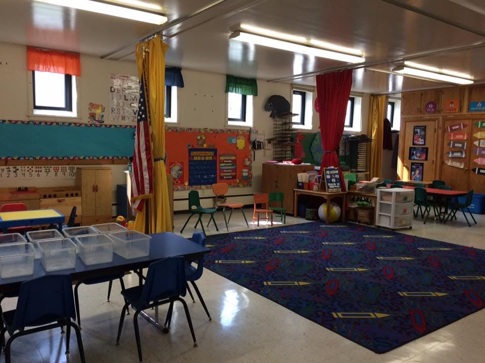 Classroom with tables, chairs, and a blue rug