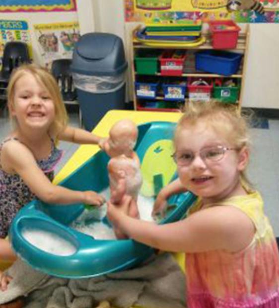 Two children bathing a doll in a toy tub