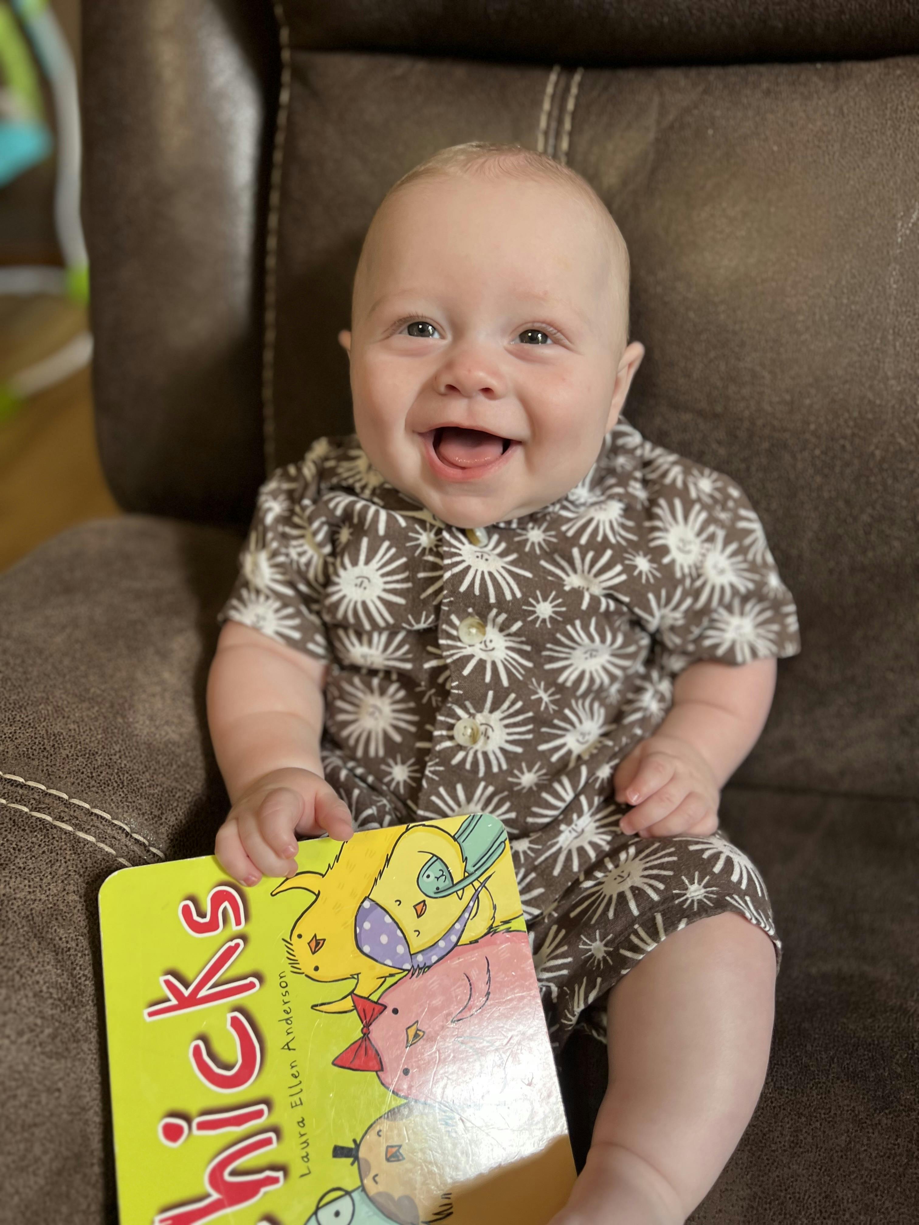Child in patterned outfit holding a book with "Chicks" on the cover
