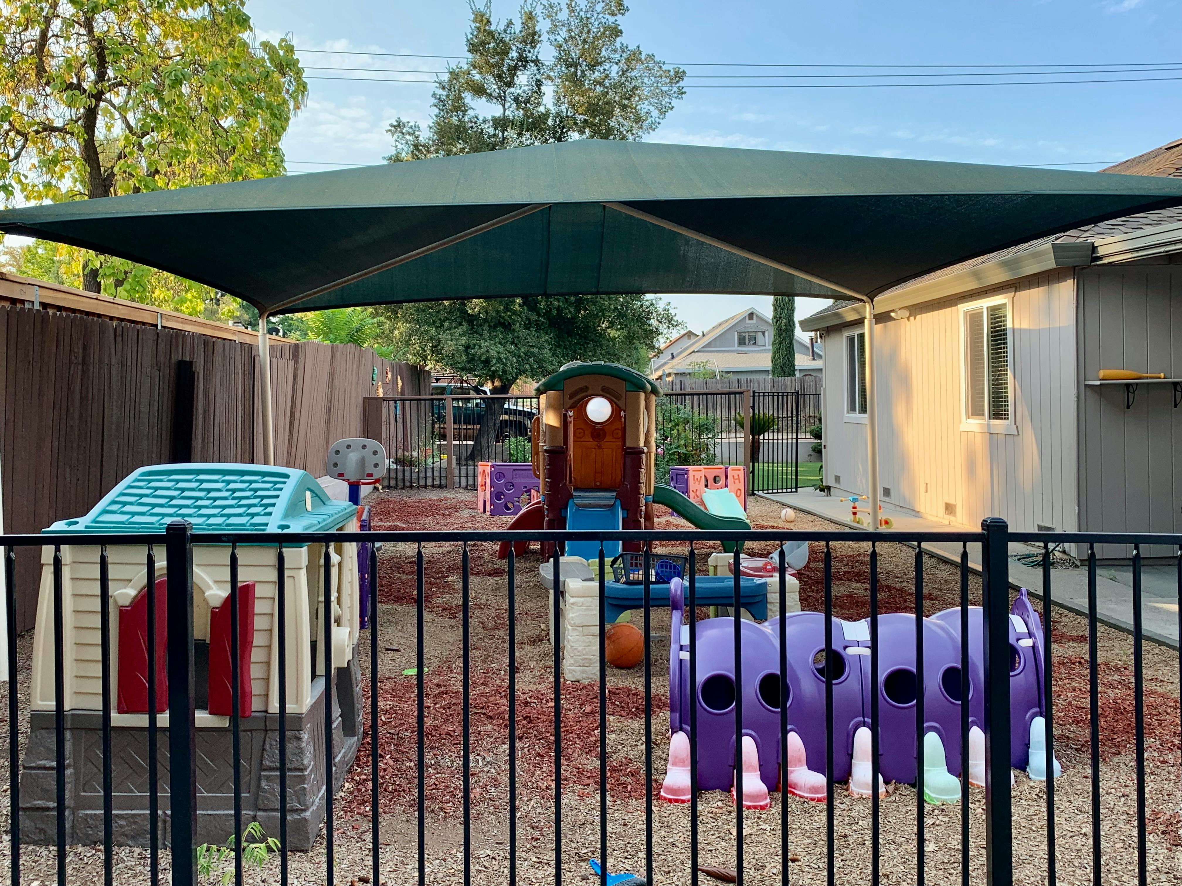 Playground with playhouses, slides, and tunnels under a large shade structure