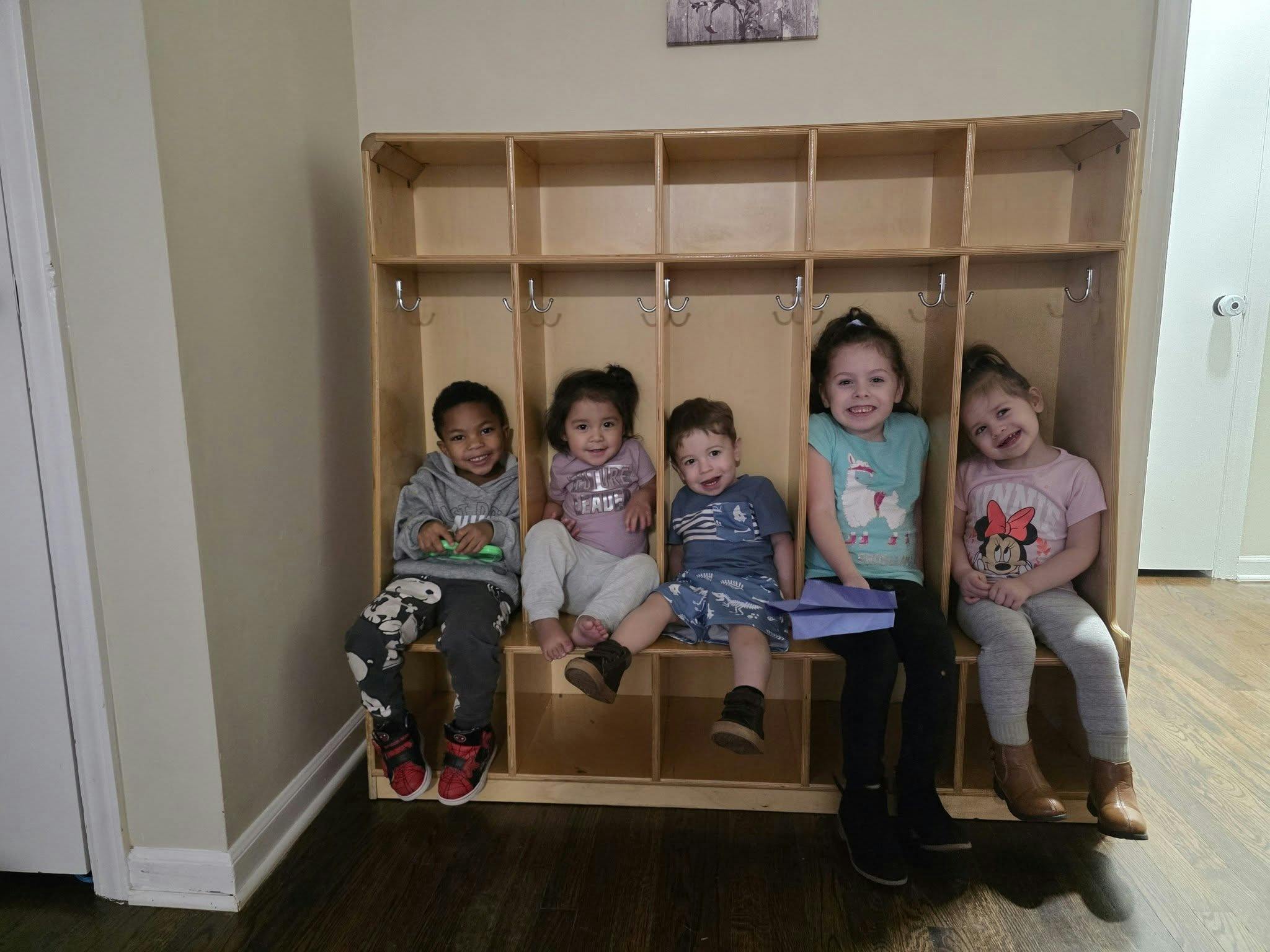 Five children sitting in cubbies in a classroom
