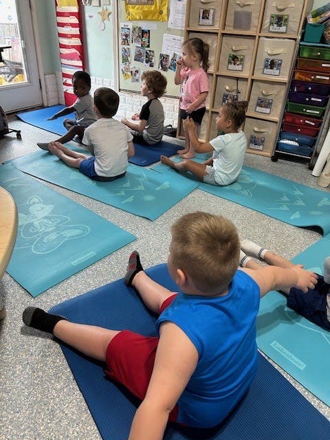 Children sitting on yoga mats in a classroom
