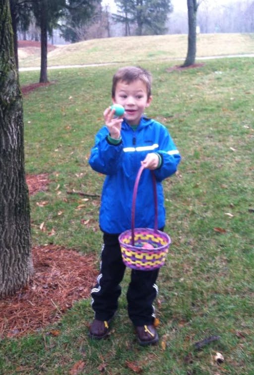 Child holding an egg and a basket outdoors