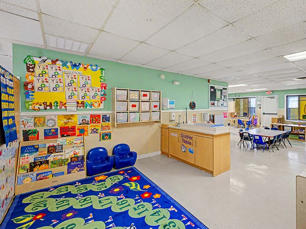 Classroom with a diaper changing station, library shelves, and tables with chairs