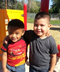 Two children standing with arms around each other outdoors