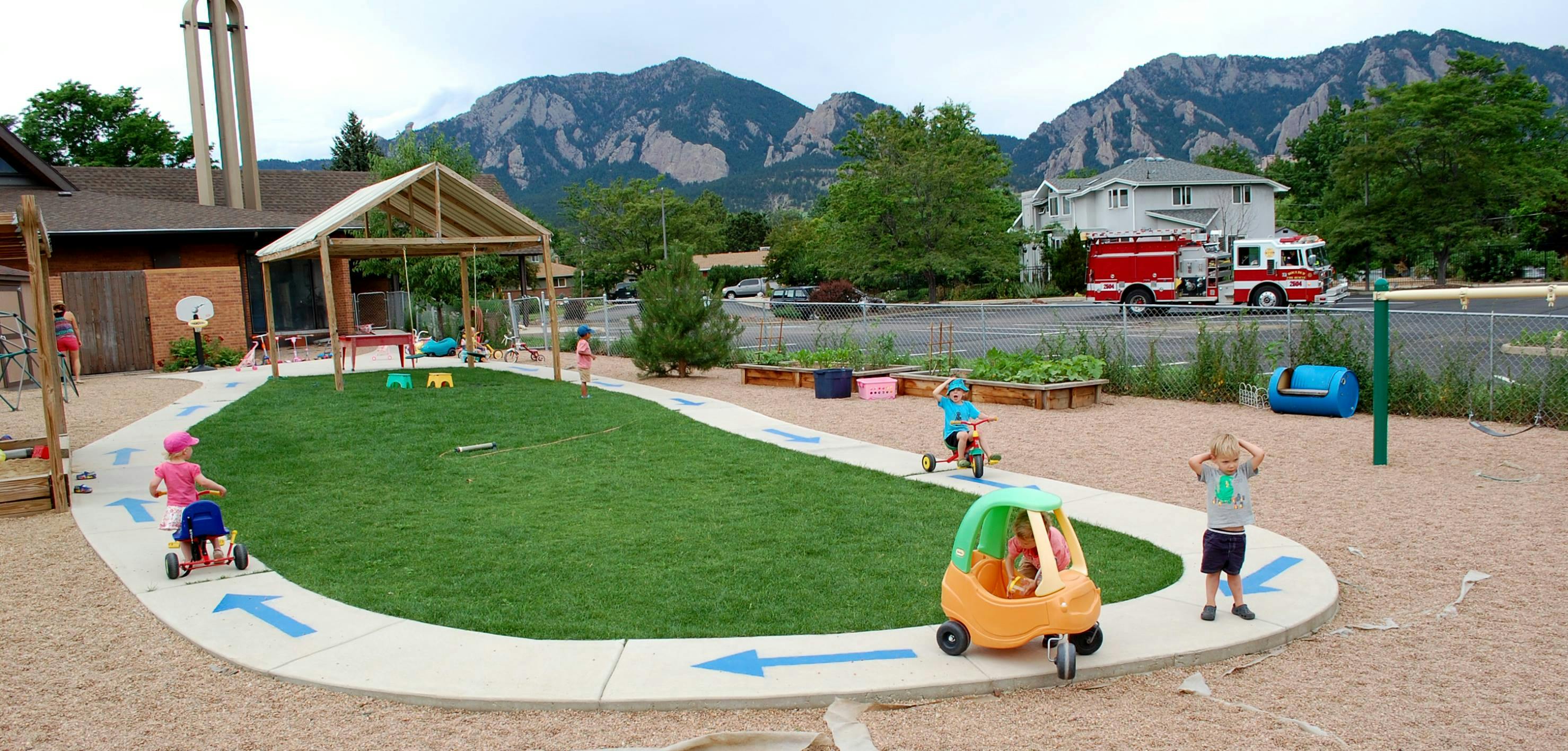 Children playing on a playground with a path and artificial grass