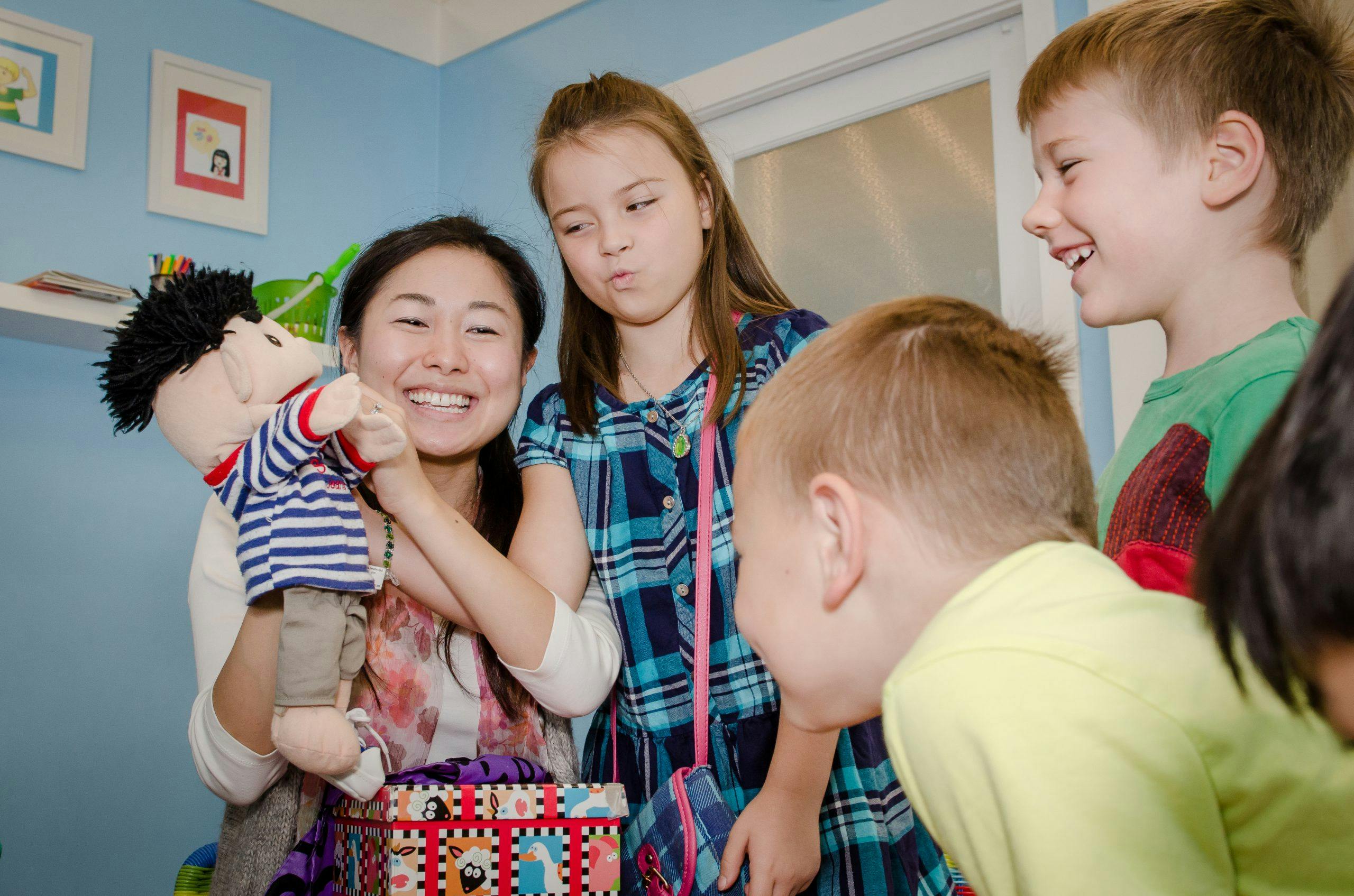 Person holding a puppet with children looking on