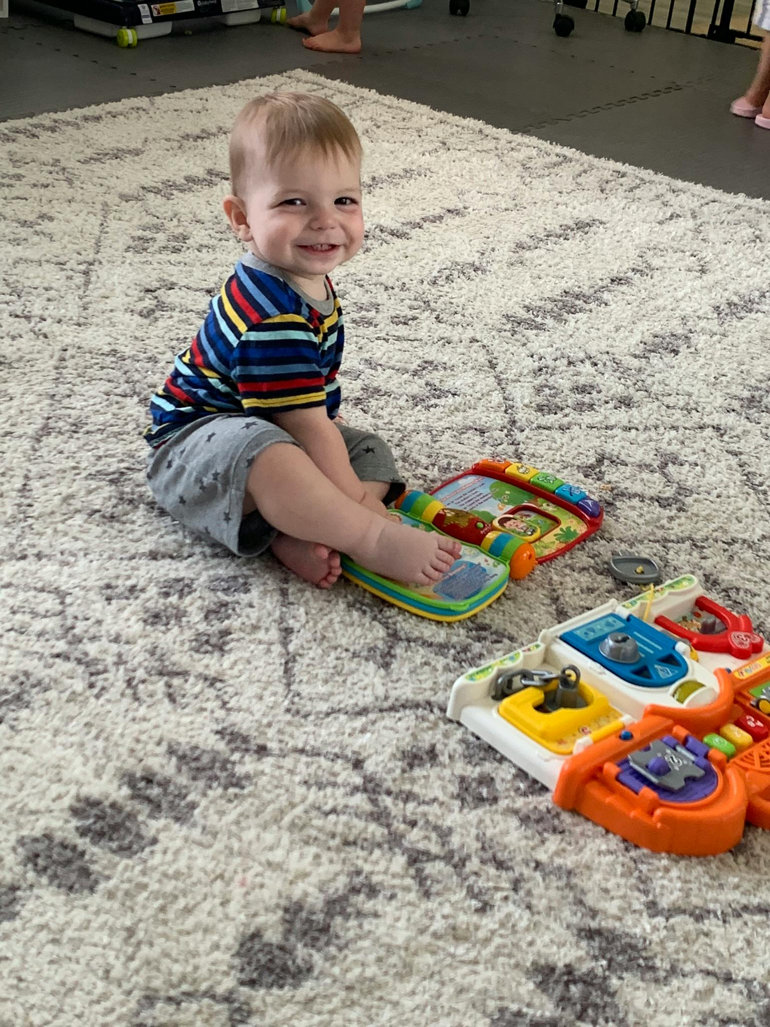 Child sitting on a rug with colorful toys