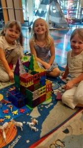 Three children playing with building blocks on a rug