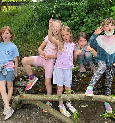 Five children posing outdoors, one giving a peace sign, another a thumbs up