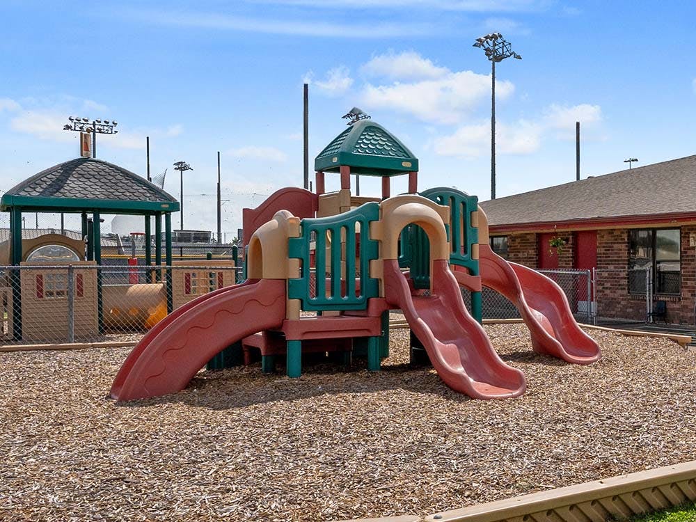 A playground with two slides and wood chips on the ground