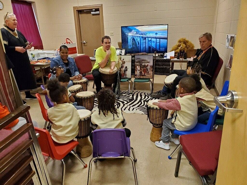 Adults and children playing drums in a circle