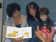 Two adults and a child reading a book together
