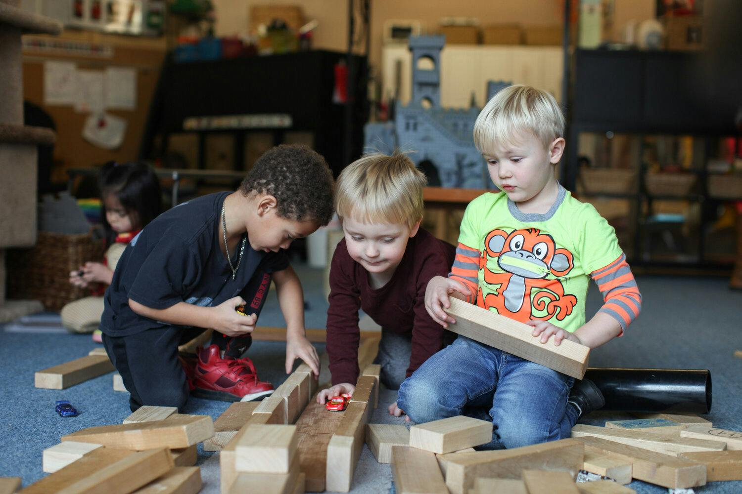 Three children playing with wooden blocks on the floor