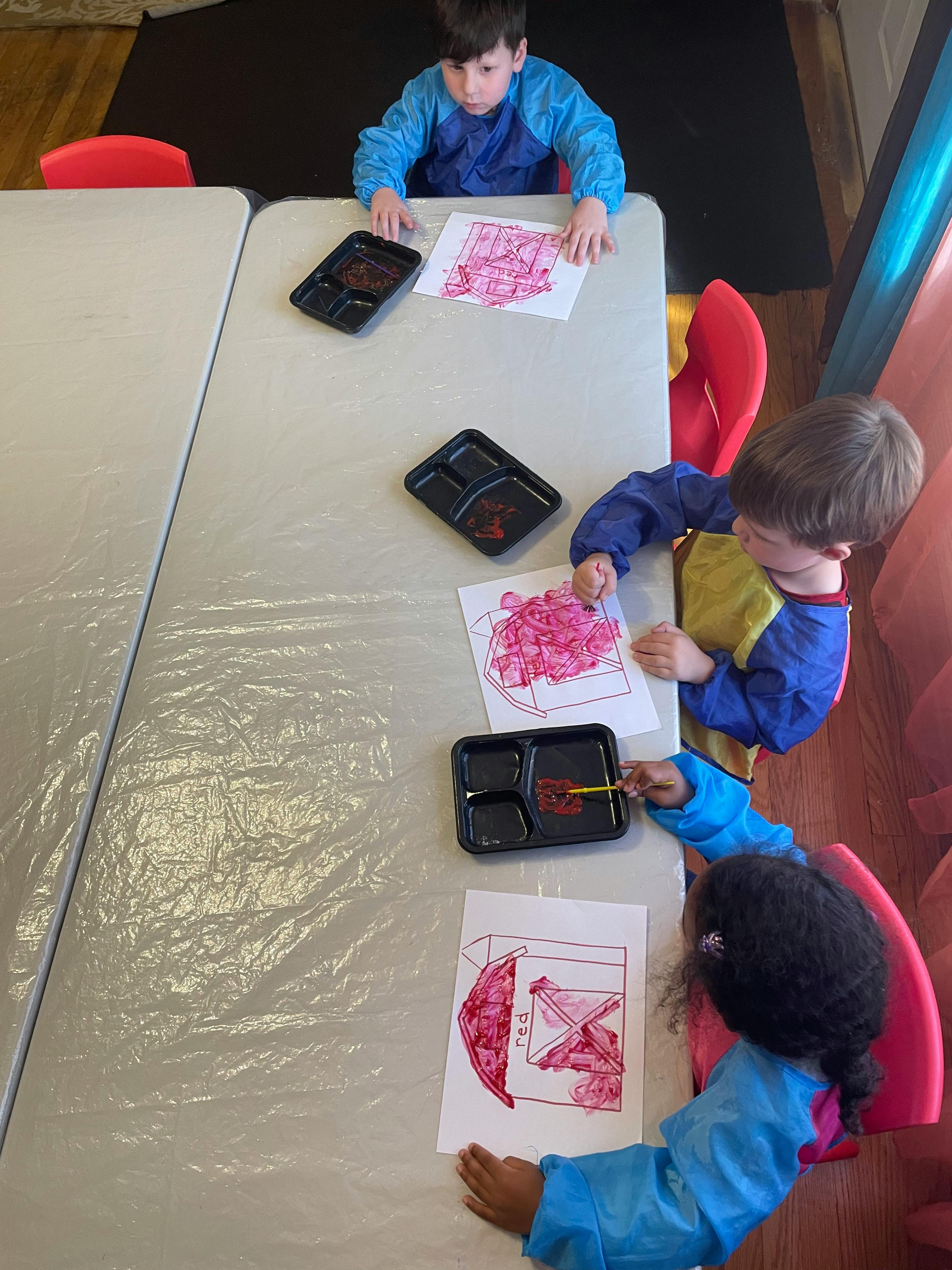 Three children painting at a table