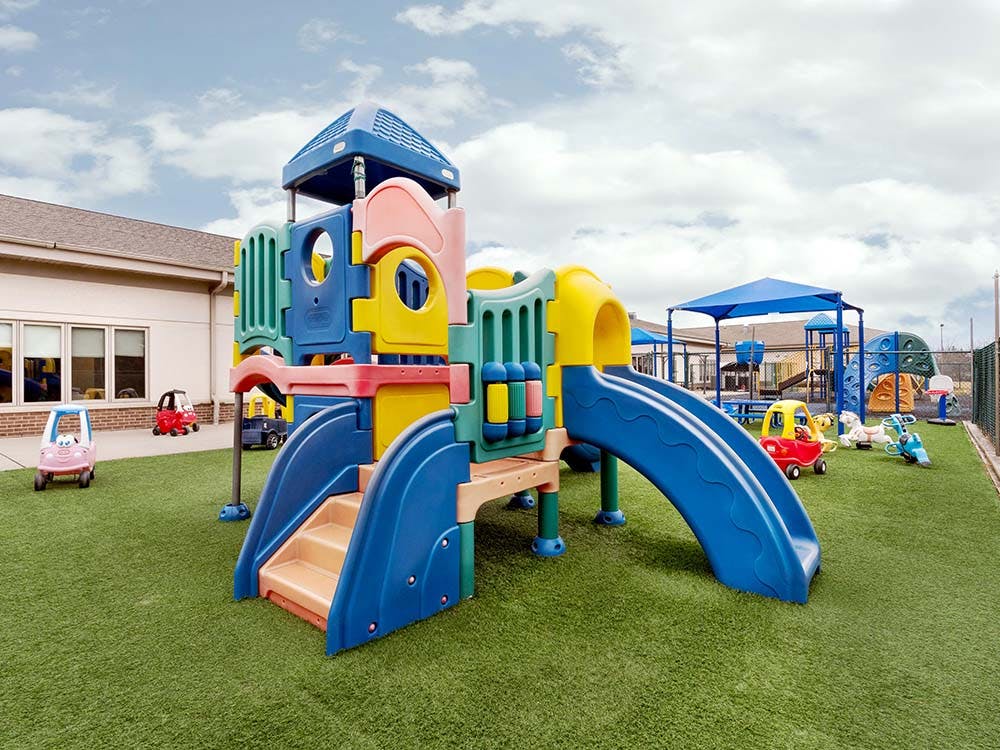 Colorful outdoor playground with slides and climbing structures on green artificial turf