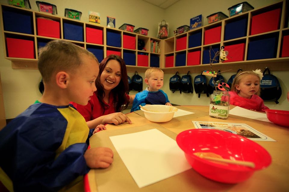 Adult and three children at a table with paper and bowls