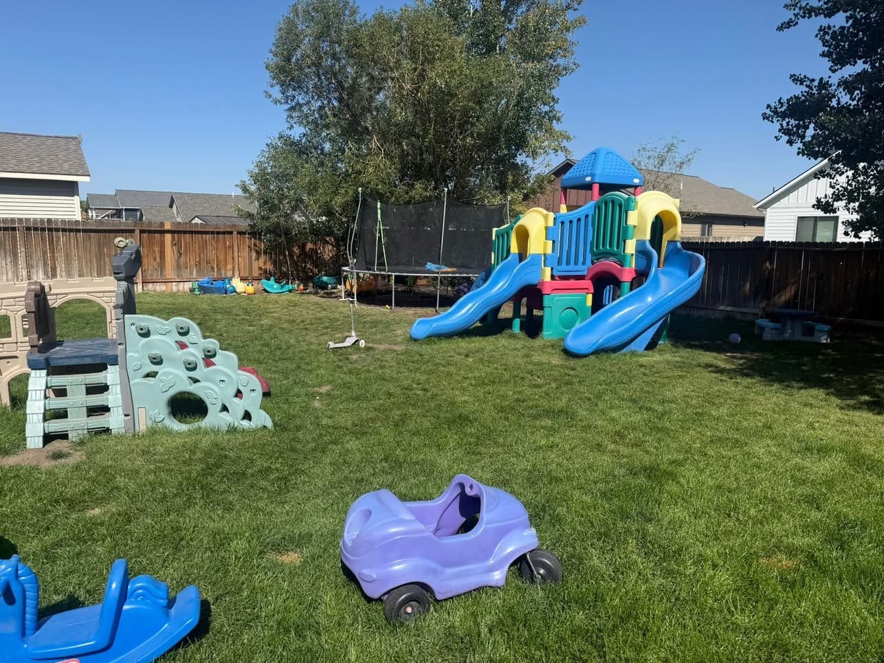 Playground with slides, climbing structure, and ride-on toys on grass