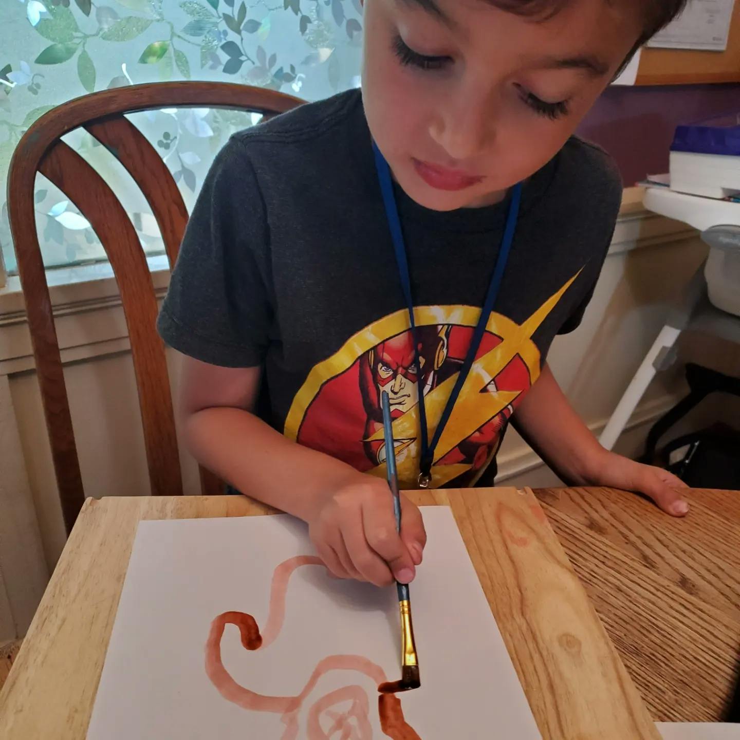 Child painting on paper with a paintbrush