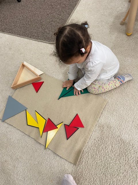 Child playing with colorful geometric shapes on a mat