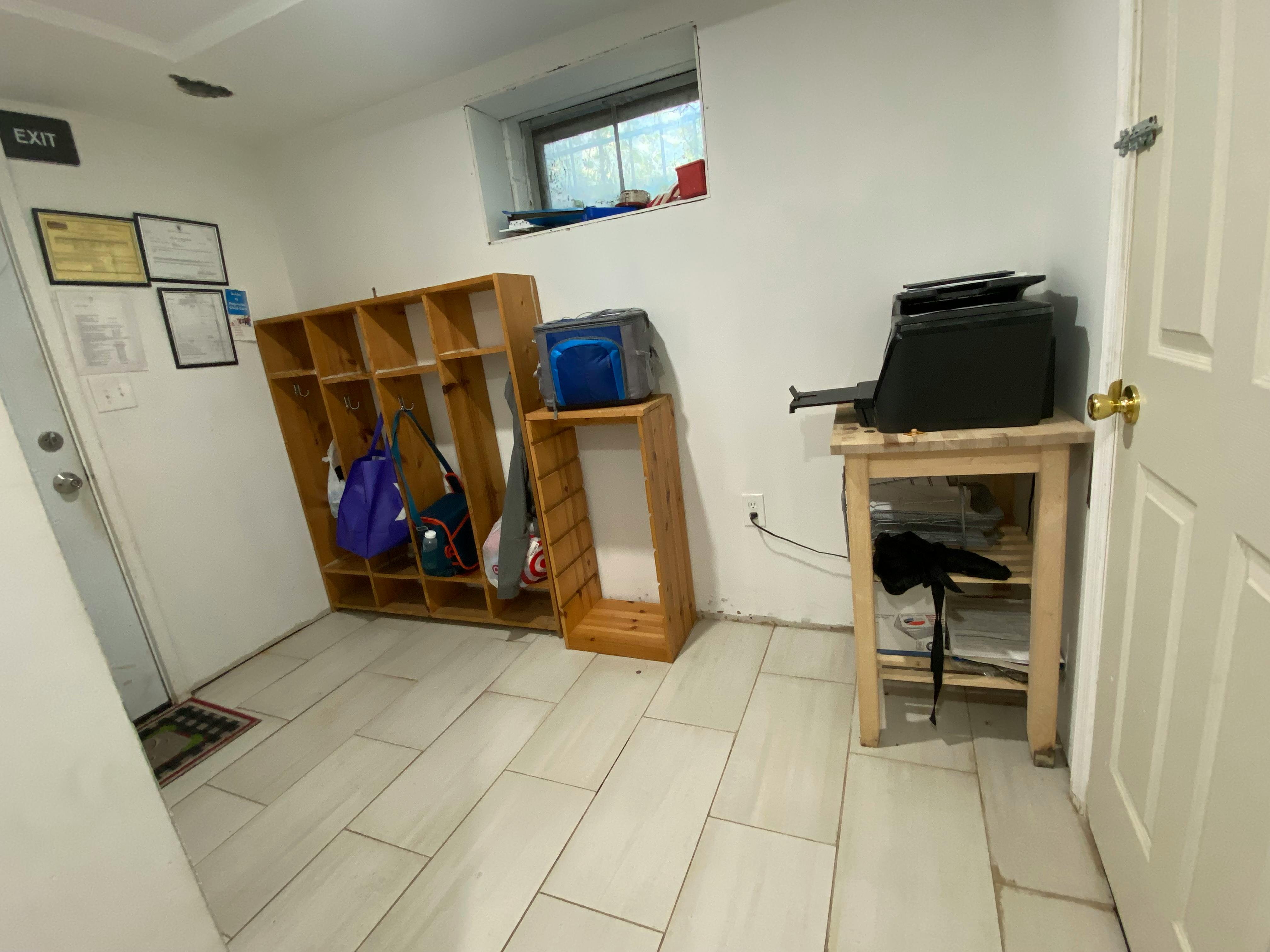 Room with wooden cubbies, a small table with a printer, and a window