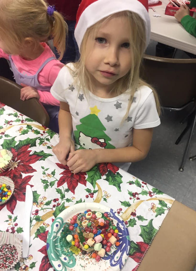 Child in Santa hat decorating a plate of treats