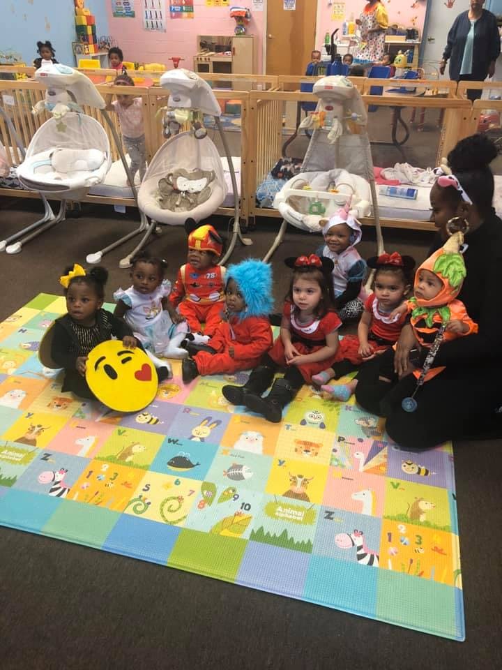 Adult and children in costumes sitting on a playmat