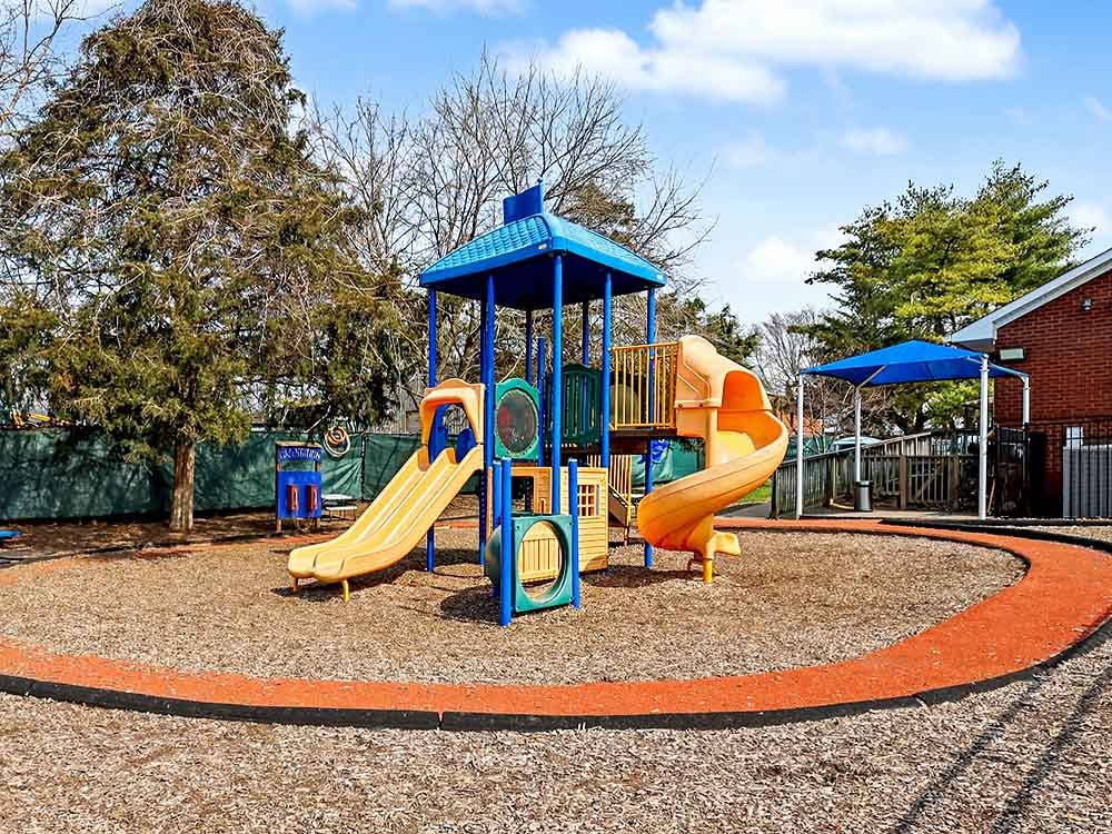 A colorful playground with yellow slides and a blue structure on wood chips